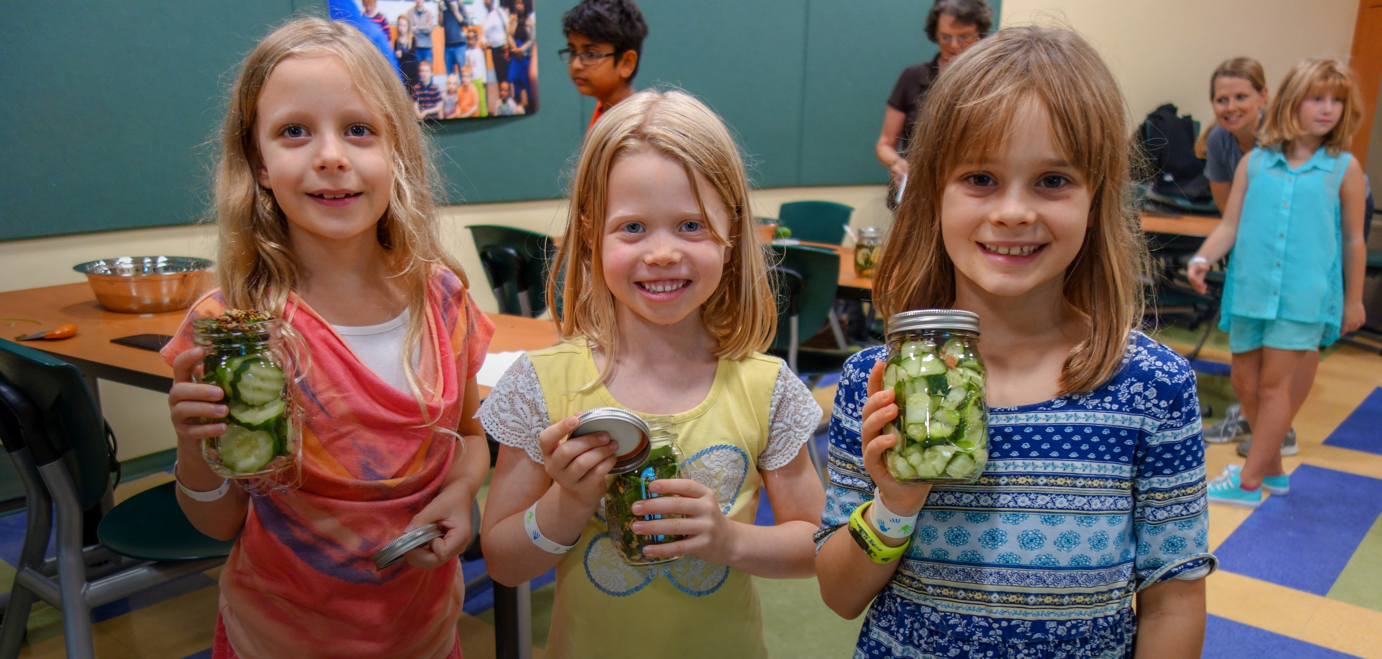 Three girl scouts smiling and holding jars with their science experiment. Programs for Scouts