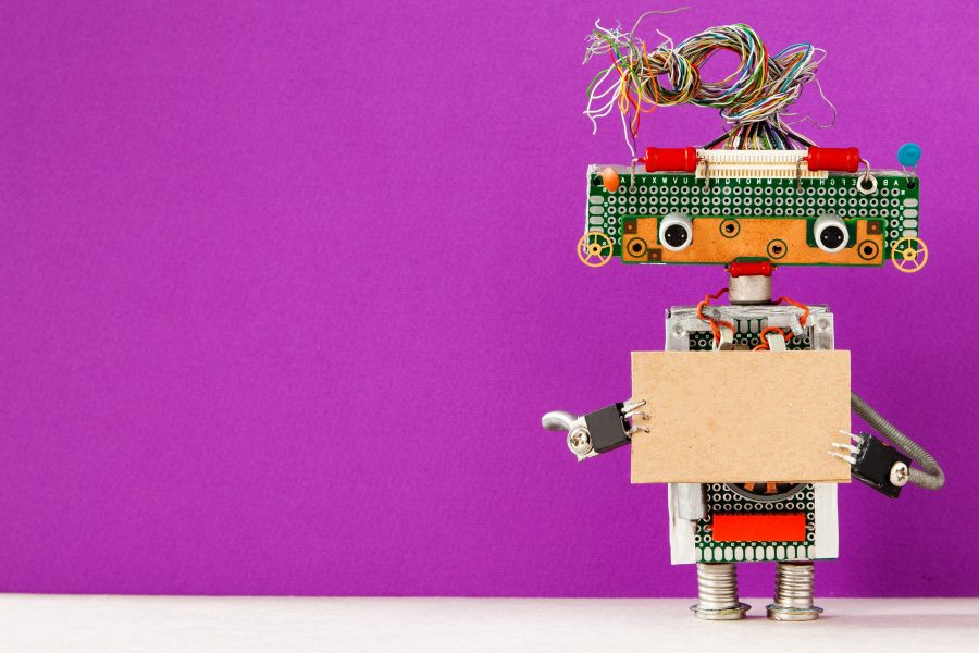 Robot with a cardboard card mockup. Creative design robotic toy holding a blank empty paper poster, purple wall background. Programs for Scouts - Girl Scouts Robotics Workshop